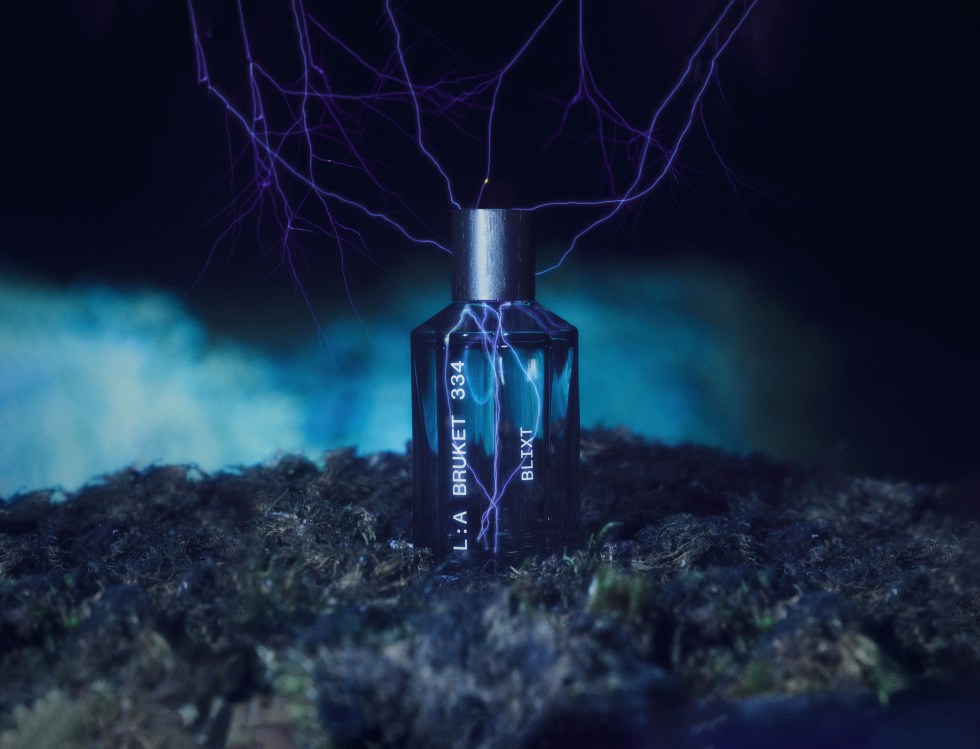 Bouteille de parfum bleu transparente posée sur le sol et frappée d'éclairs fins