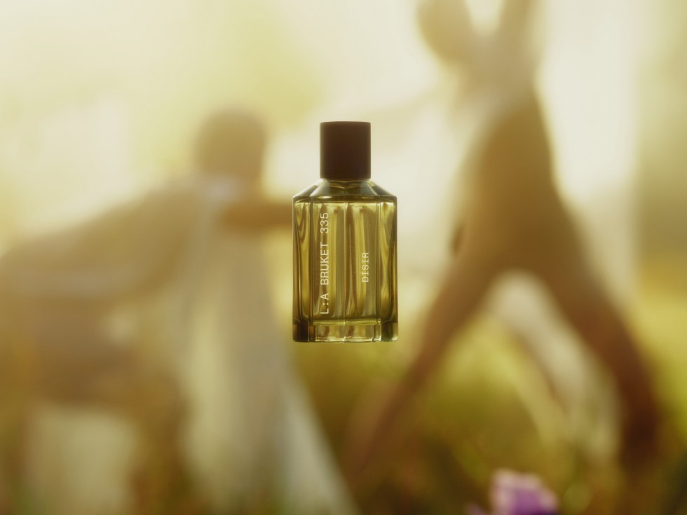 Bouteille de parfum jaune avec des silhouette dansantes sous un soleil.